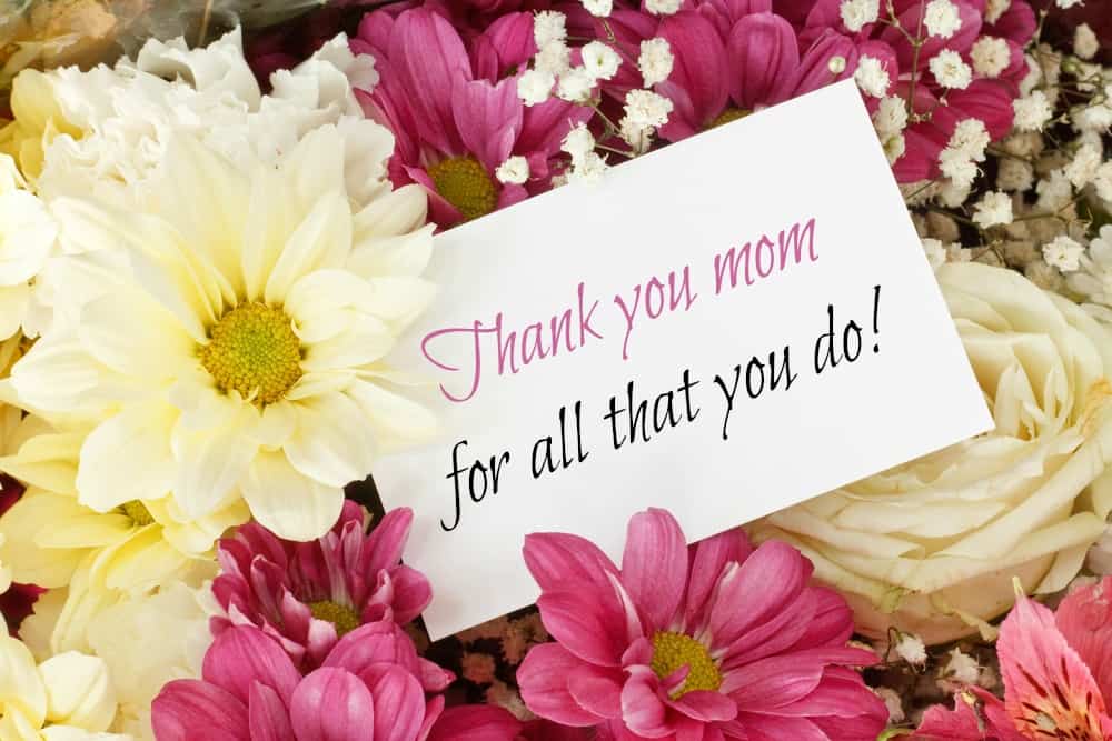 A note saying thank you mom surrounded by pink and yellow flowers