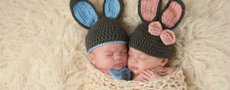 Sleeping newborn twins wearing bunny hats and swaddled together