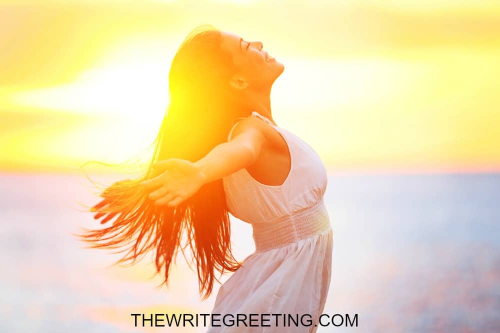 Beautiful woman in a white dress embracing the golden sunshine