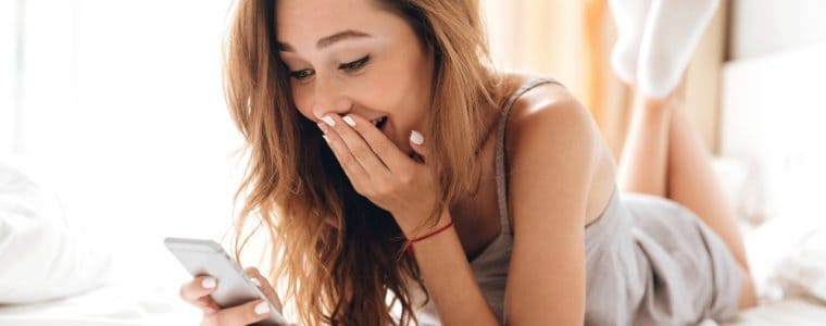 Young woman lying in bed texting long distance boyfriend