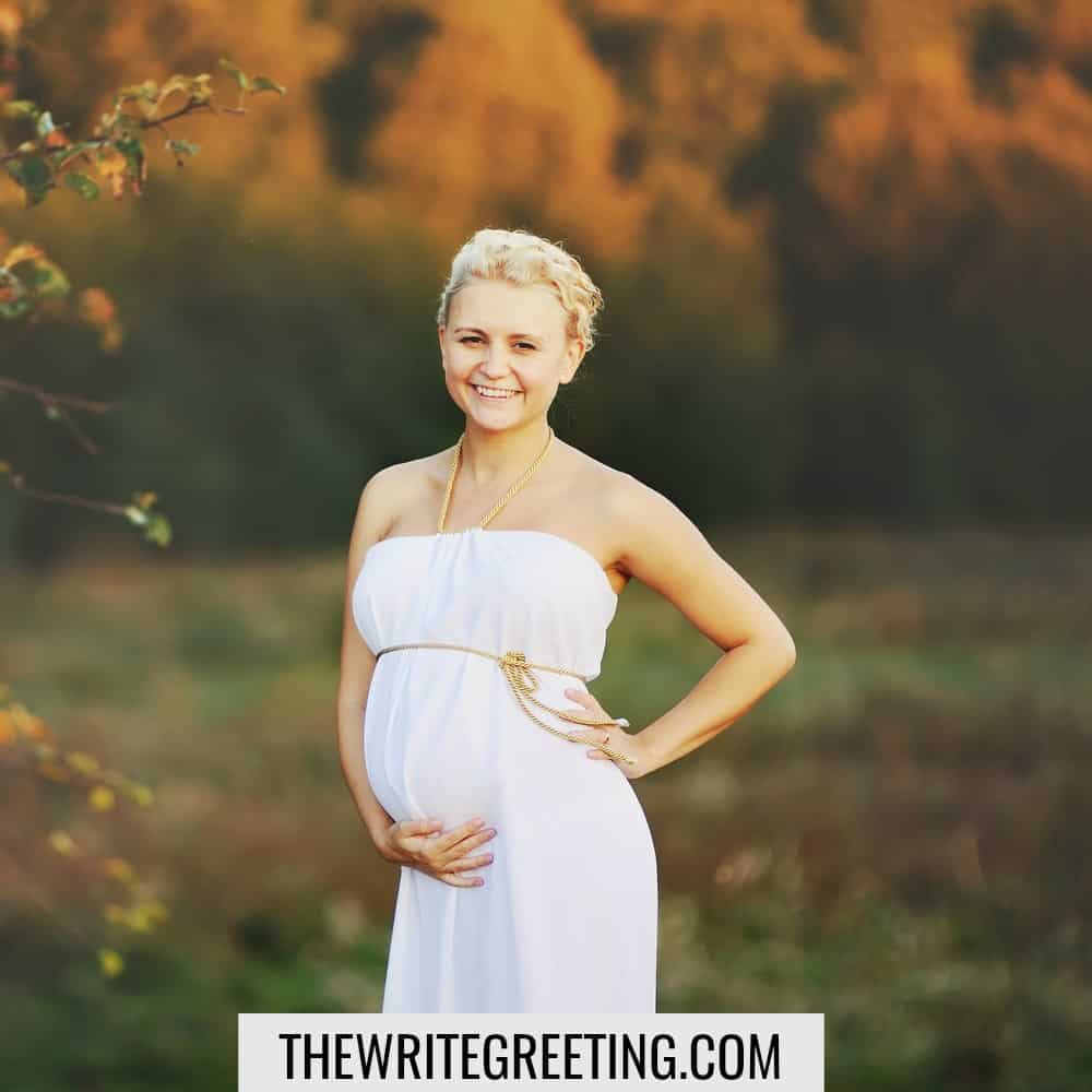 Young caucasian pregnant woman in a white greek dress outside.