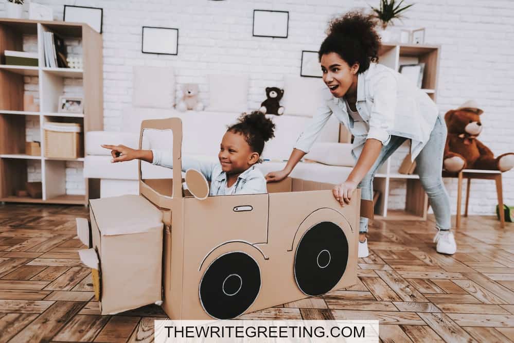 babysitter playing with kid in cardboard car