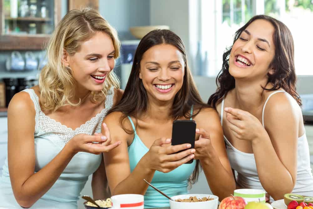 Young women smiling at their smart phone