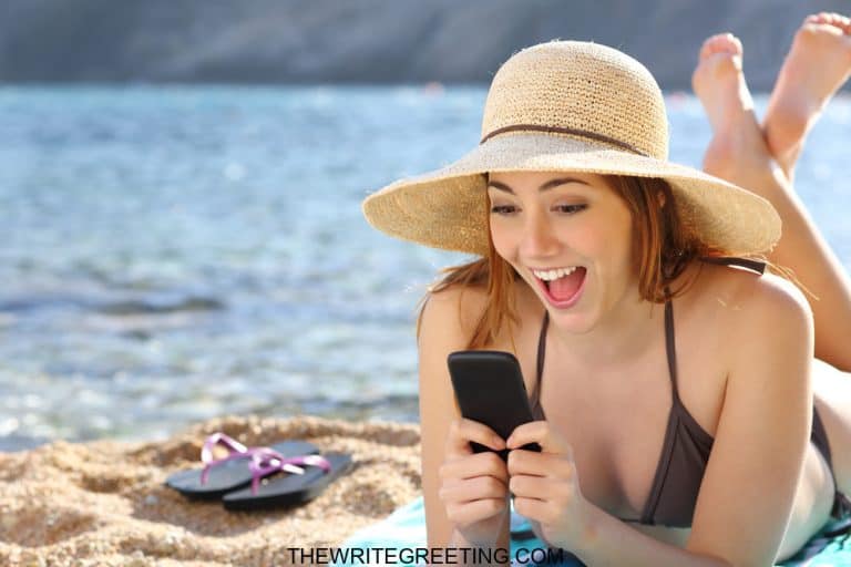 Young girl laughing at phone on beach