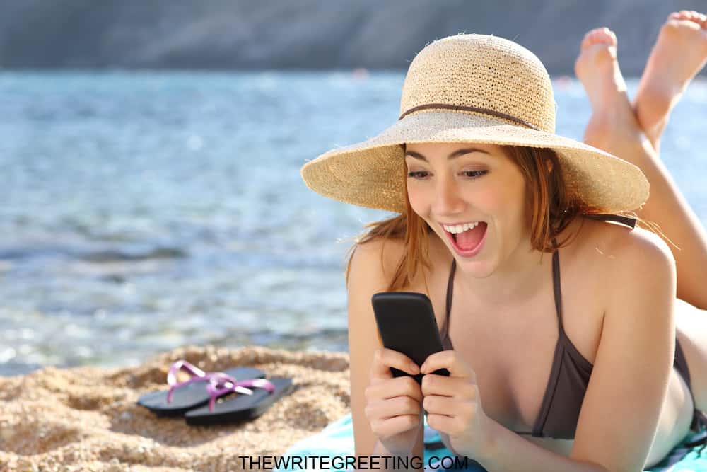 Young girl laughing at phone on beach