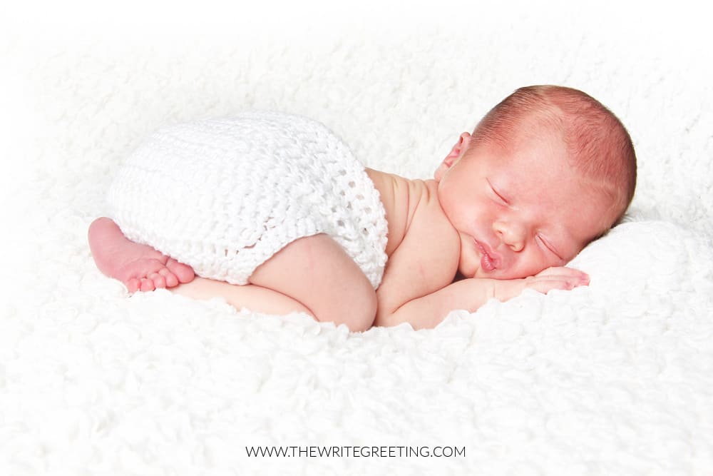 Newborn baby boy asleep on a white blanket.