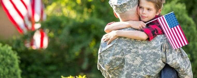 Young boy hugging military dad
