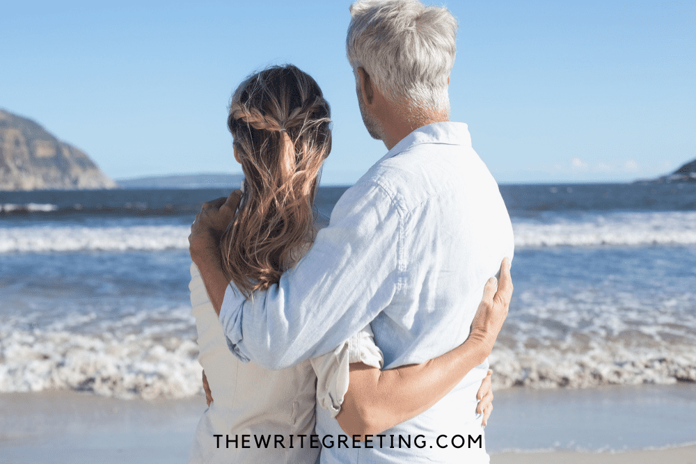 couple celebrating 25th wedding anniversary at beach staring at ocean