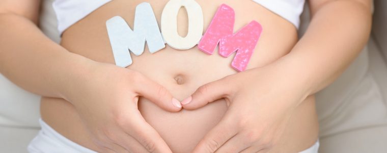 Woman showing pregnant belly with heart sign