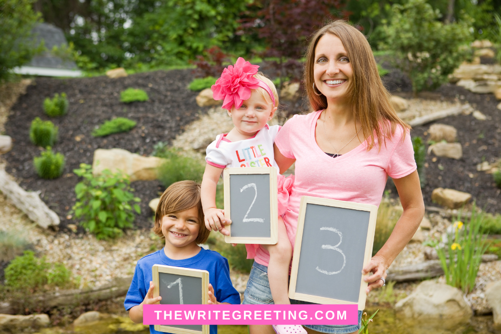 Mom holding young daughter, son beside holding 1,2,3 cards announce pregnancy