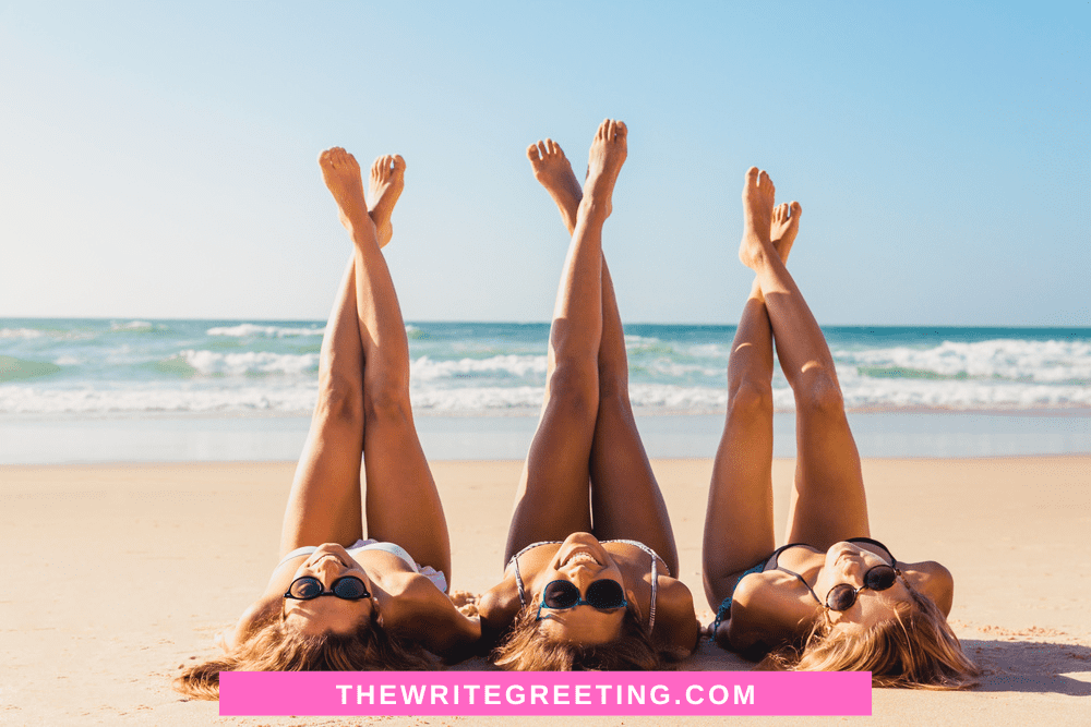 3 young girls sitting on beach with legs in the air