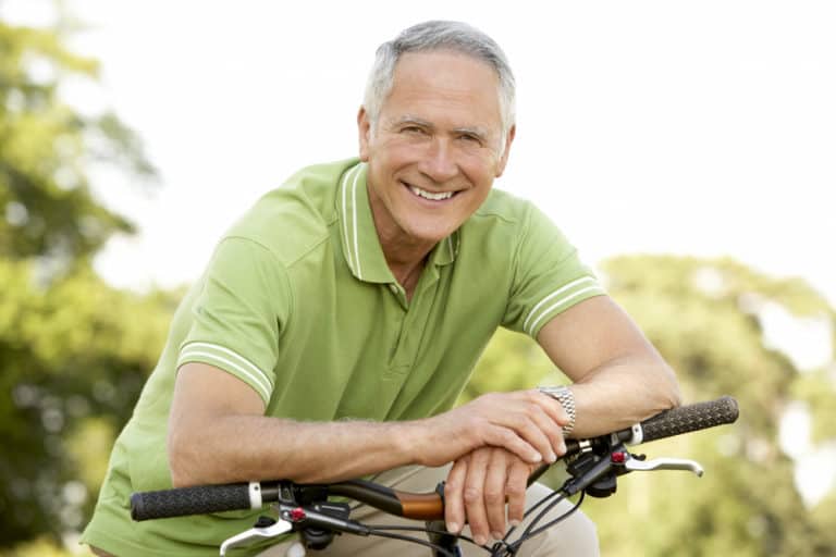 Older man in light green jumper leaning on bike