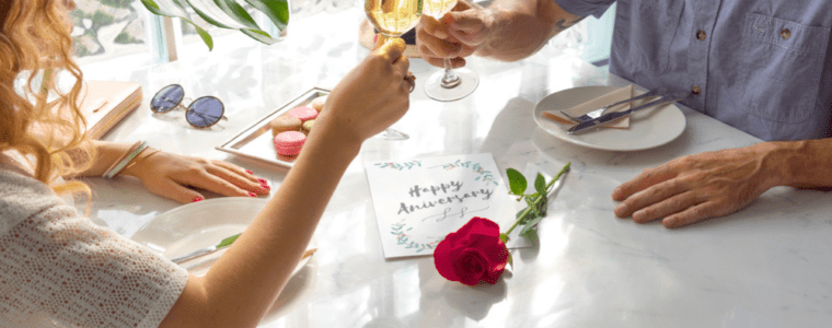 Couple celebrating anniversary with champagne glasses, red rose