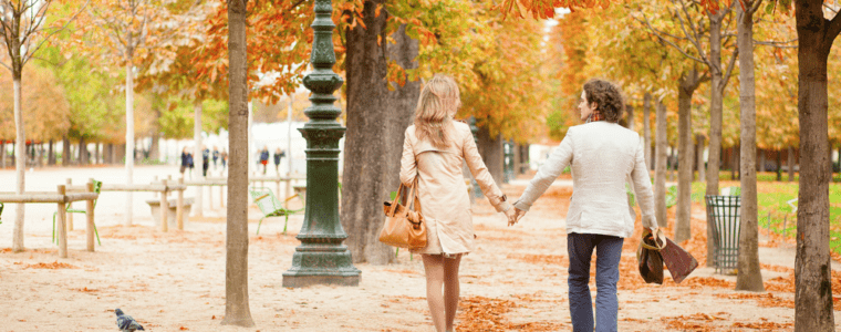 Couple holding hands walking through fall trees
