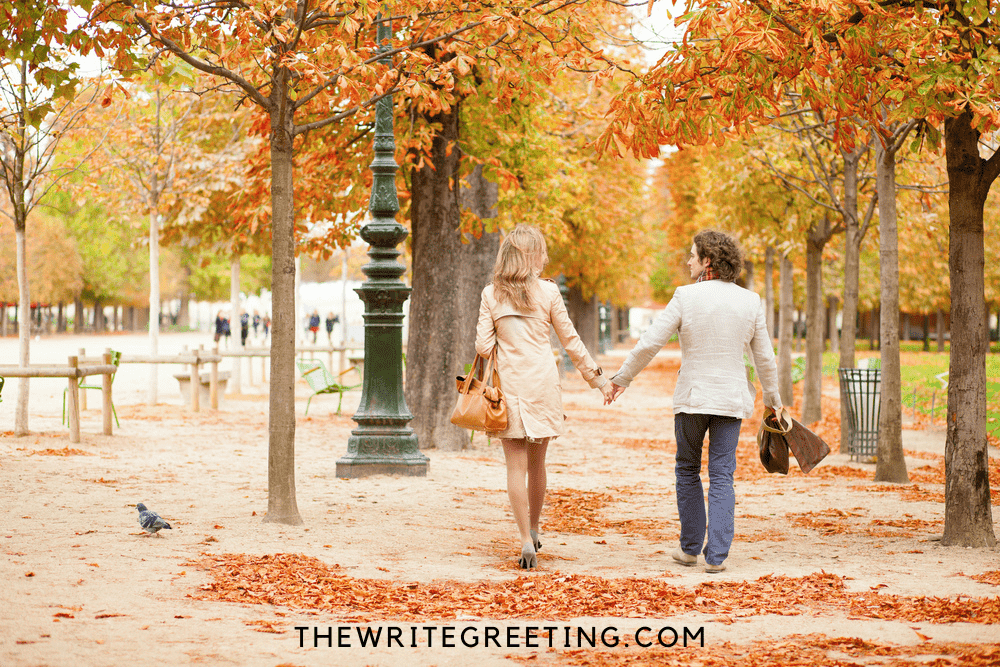 Couple holding hands walking through fall trees