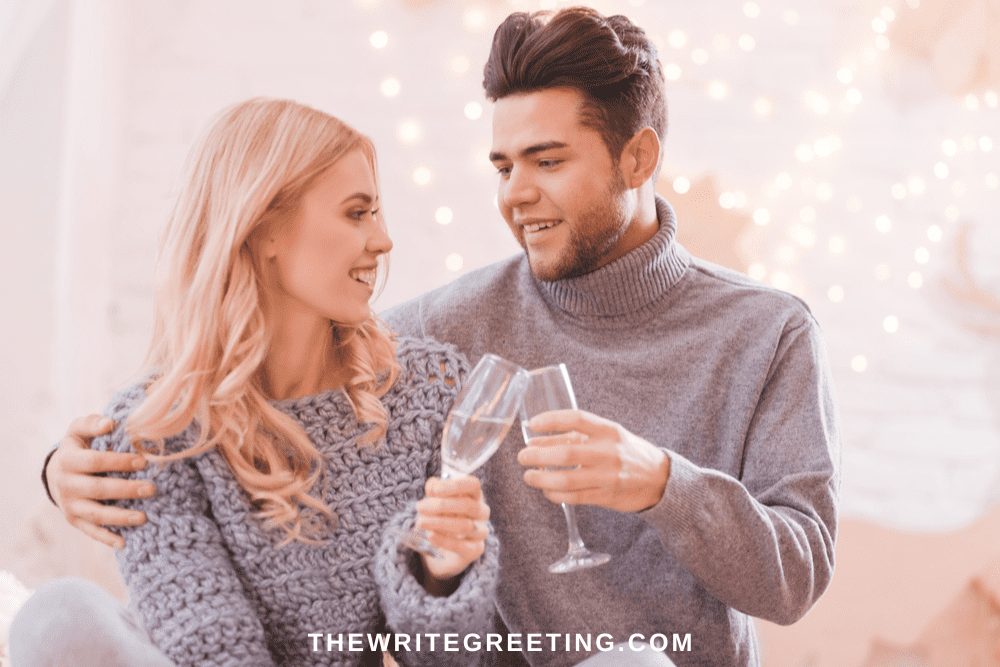 Young couple clinking champagne glasses in grey sweaters