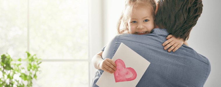 Little girl hugging dad holding valentine heart card