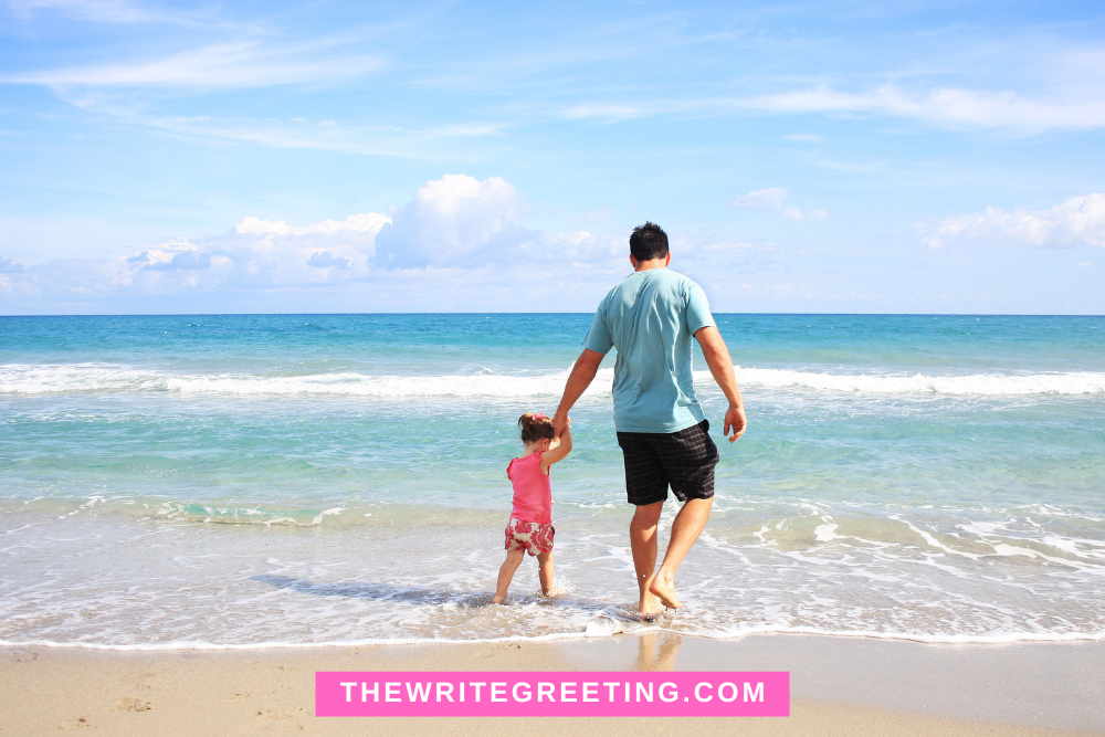 Young father with toddler daughter standing in ocean at beach