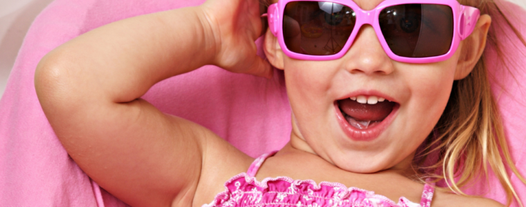 A sassy little girl all dressed i pink with pink sunglasses