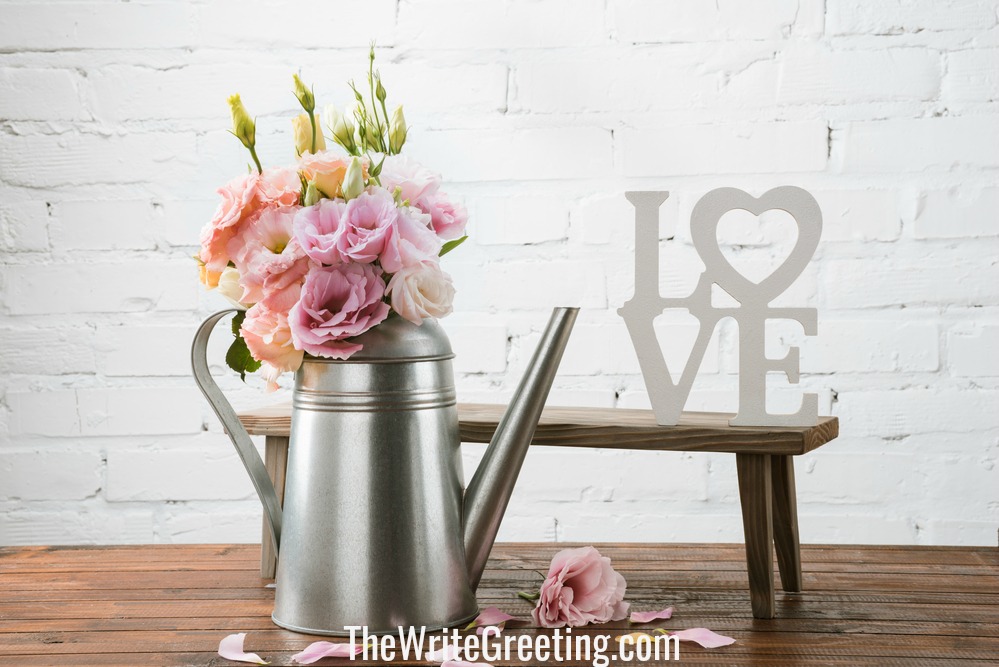 Love sign beside silver vase with pink flowers