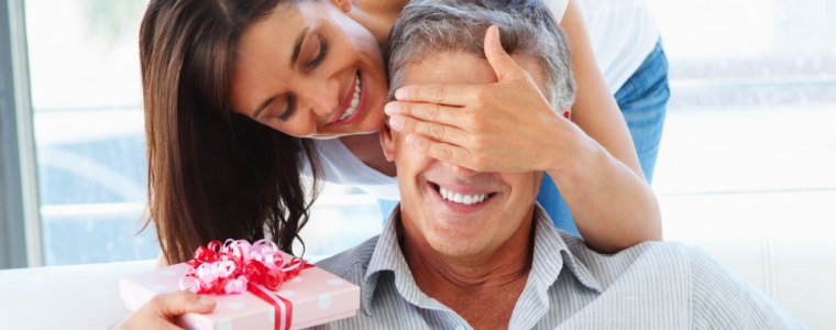 woman surprising man with gift on his birthday