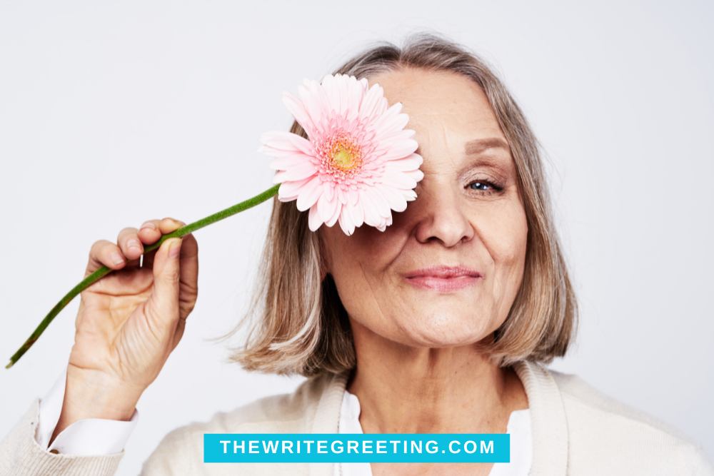 A 60 year old woman holding a white and pink flower