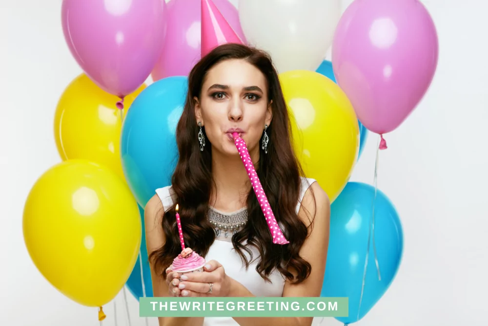 Long haired girl blowing birthday decorations with balloons behind her